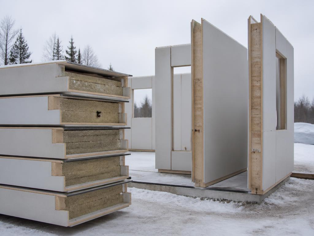 Interlocking Nordika WALL-LINK R-36 structural wall panels stacked and partially assembled on a winter jobsite